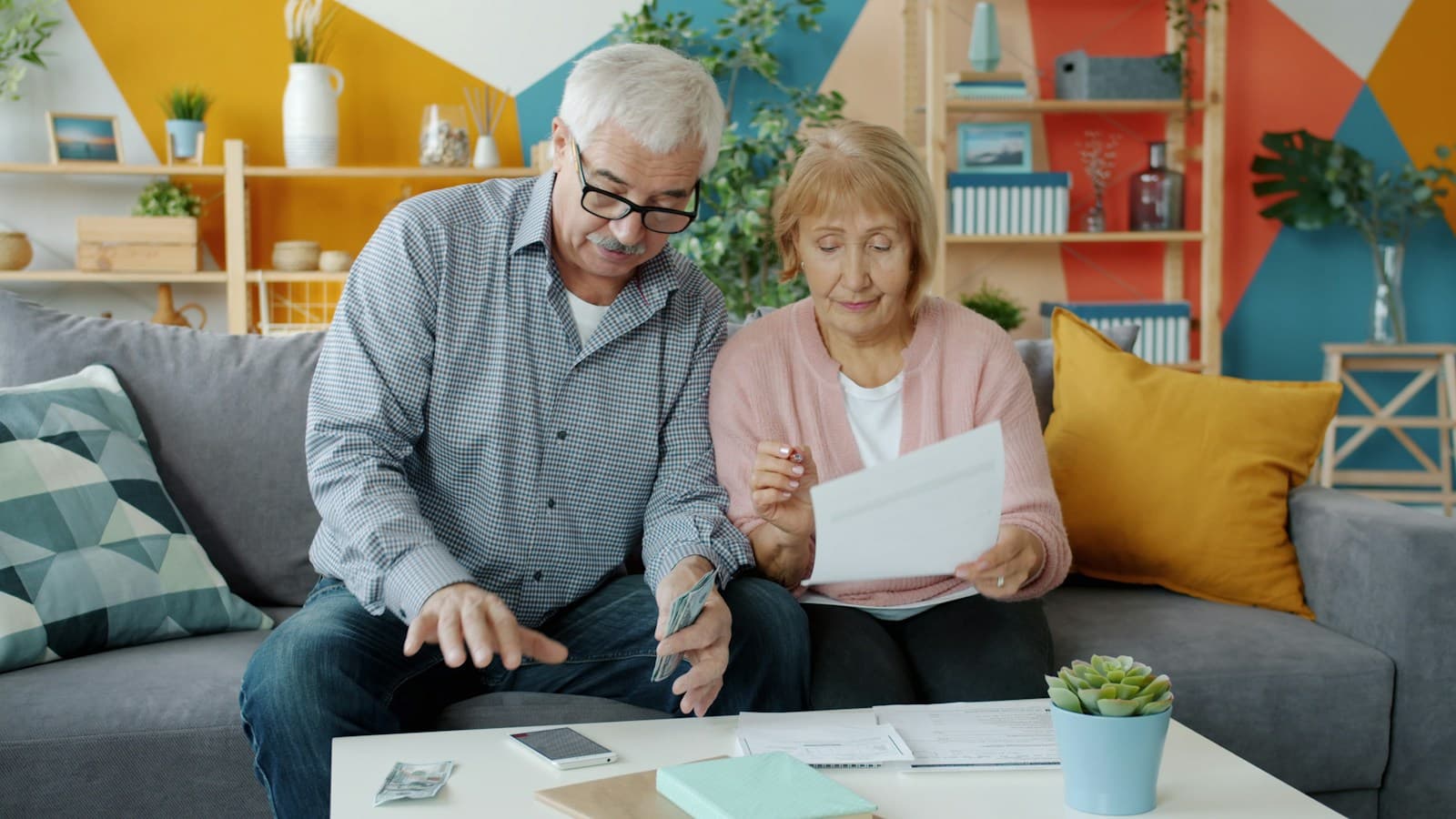 Un couple âgé regarde des papiers sur son canapé